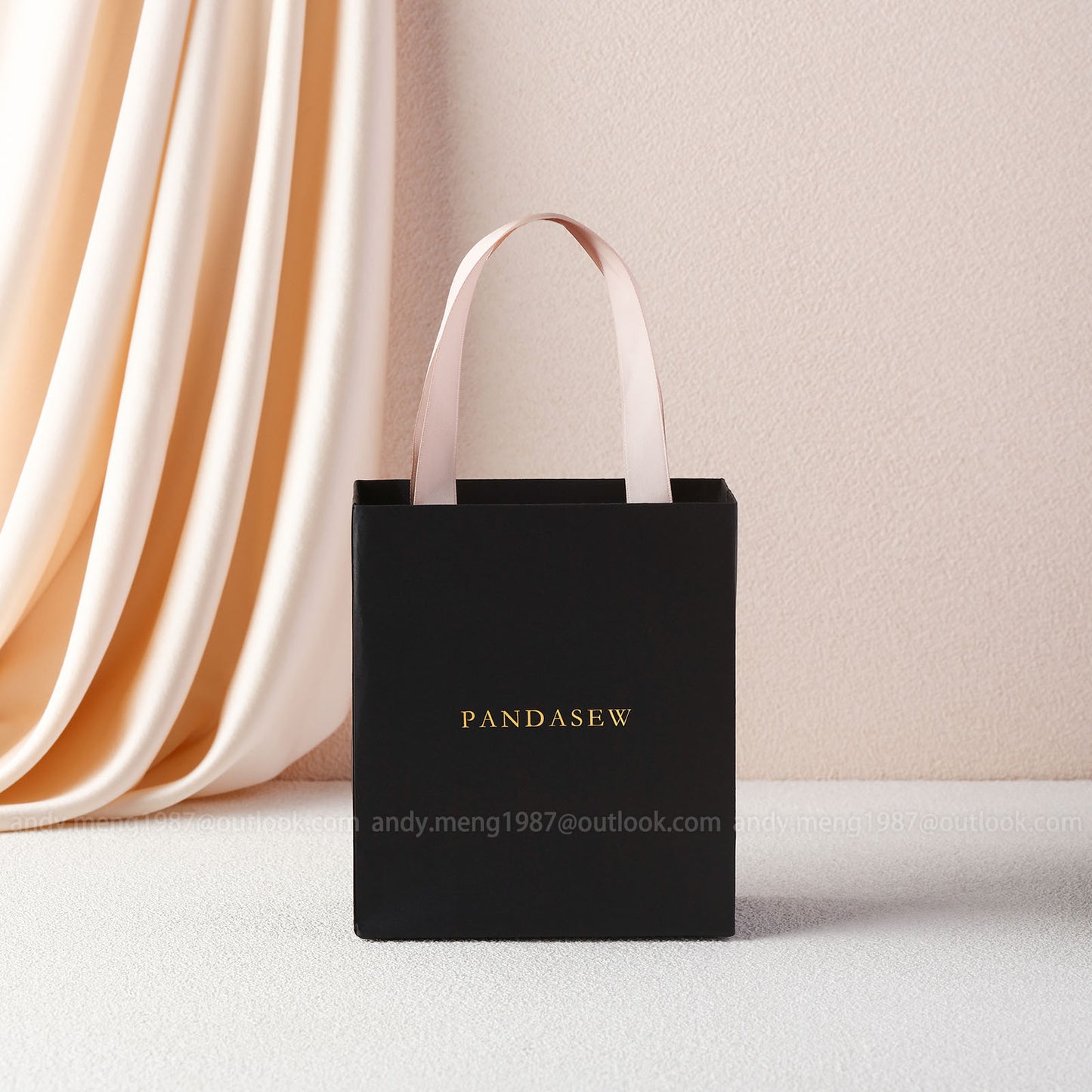 black paper bag with a gold debossed logo. The ribbon is also texture cotton ribbon