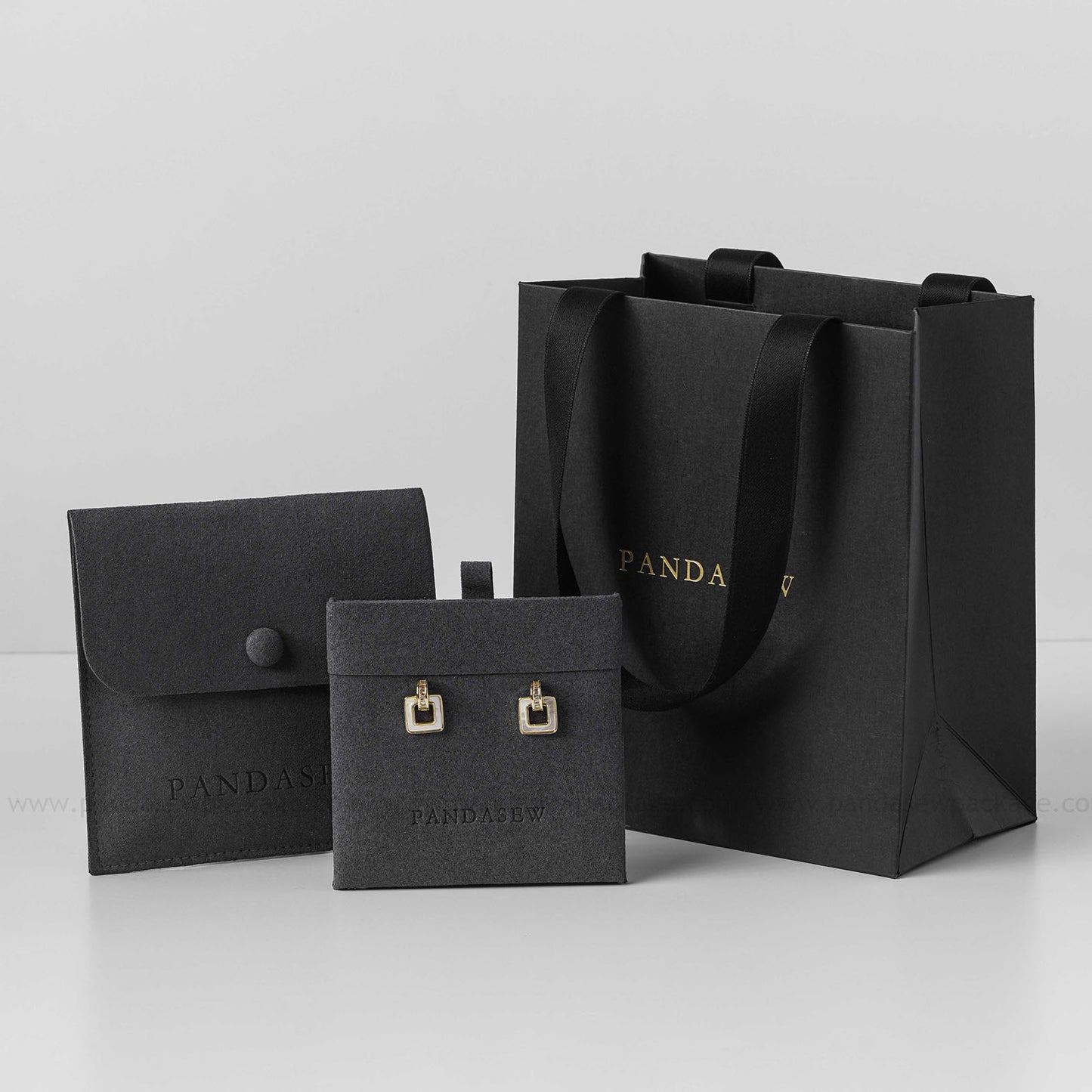 Black paper bag with black jewelry bag and jewelry pad