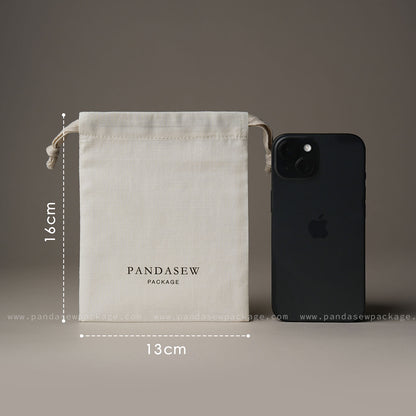 Size comparison. Medium 13x16cm drawstring bag shown next to an iPhone to demonstrate capacity.
