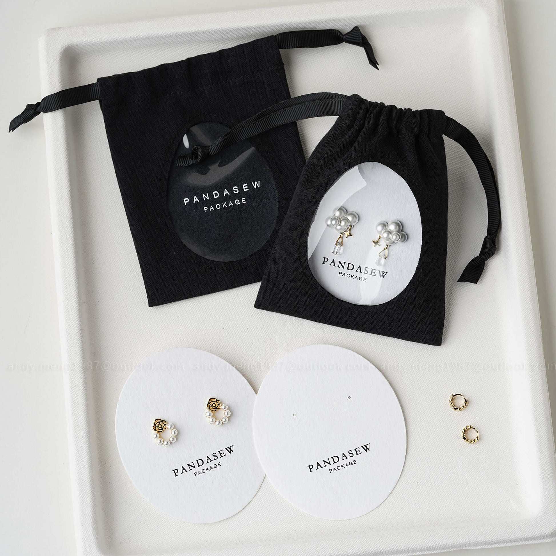 Black cotton jewelry bags with custom logo, transparent window, displaying earrings and recyclable packaging by Pandasew
