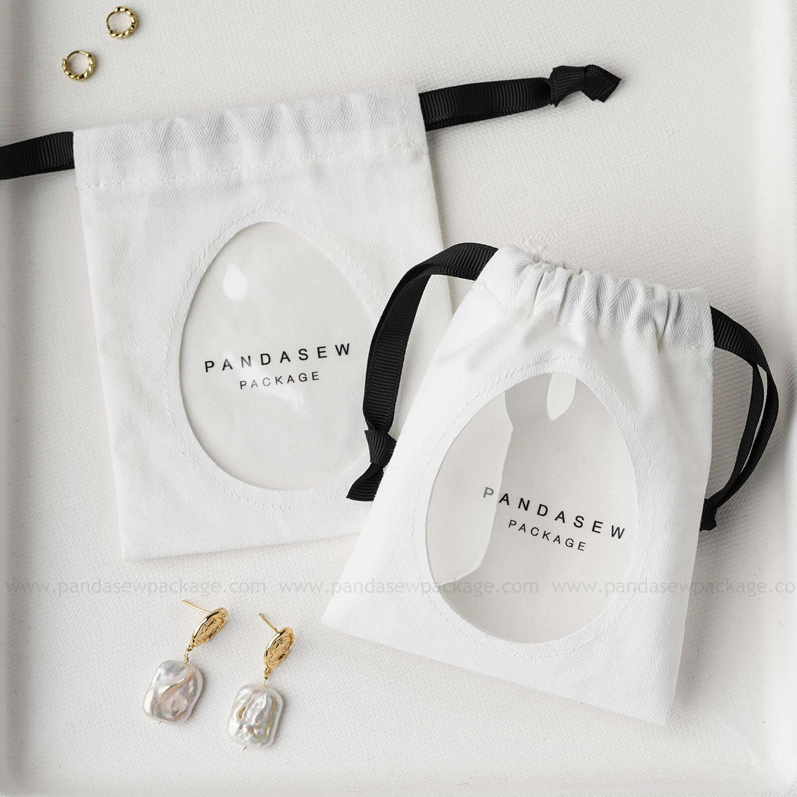 Cotton jewelry drawstring bags with custom logo, featuring transparent windows. Eco-friendly earring and bracelet packaging.