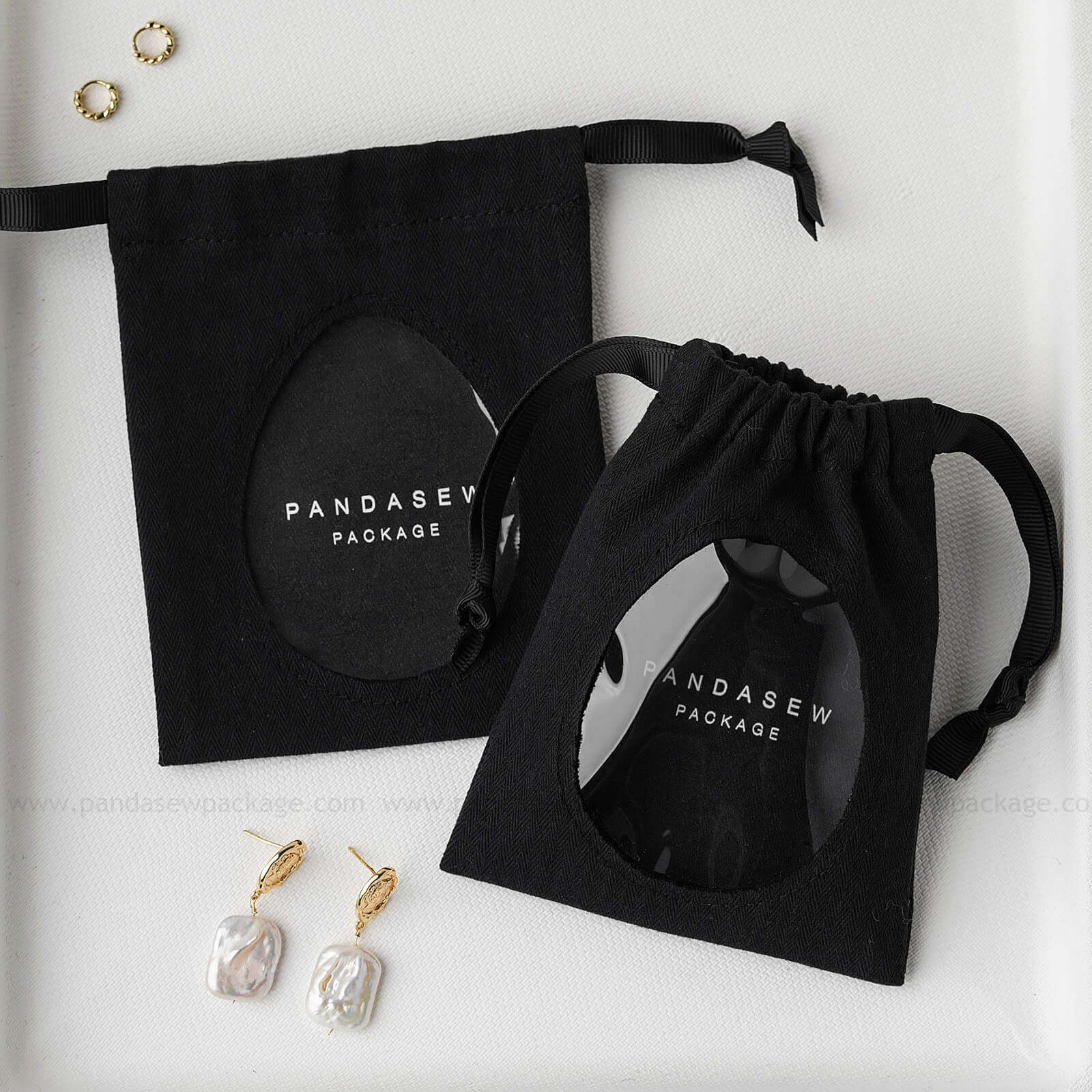 Pandasew black custom logo cotton jewelry drawstring bags with transparent window showcasing earrings and rings.