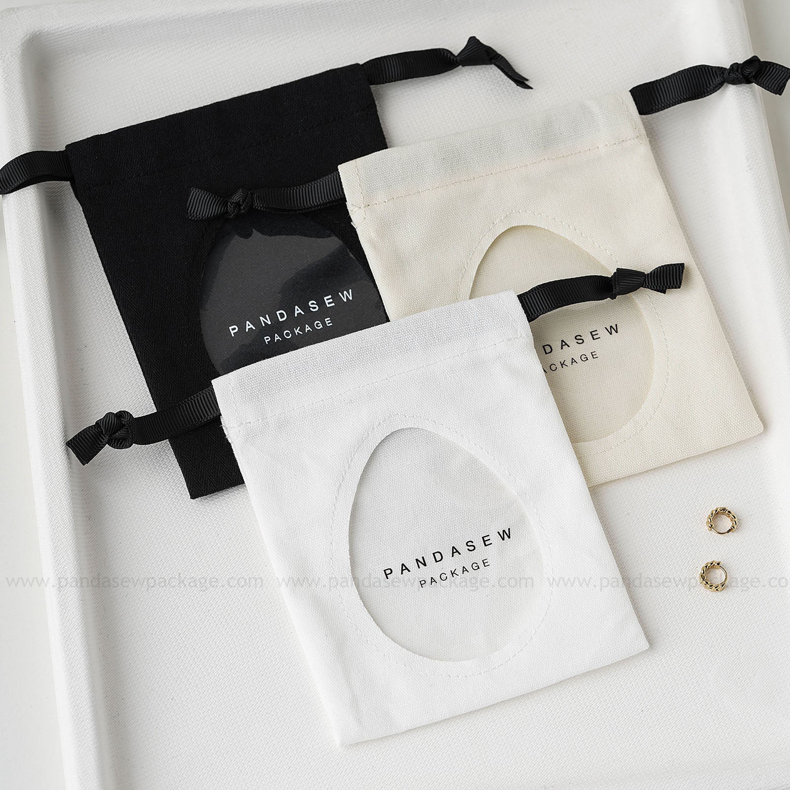 Pandasew custom logo cotton jewelry drawstring bags in black, beige, and white with transparent window, ideal for eco-friendly jewelry packaging.