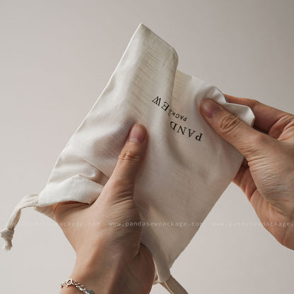 Hand holding custom pouch to demonstrate the soft, flexible, yet durable cotton linen material quality