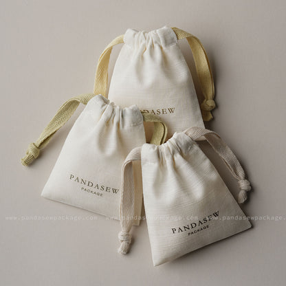 Set of three custom printed drawstring bags in different sizes. Off-white organic cotton packaging for small businesses.