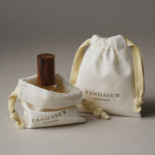 Custom logo jewelry packaging bags. Organic cotton linen drawstring pouches for gifts. Medium size bag shown holding perfume bottle.