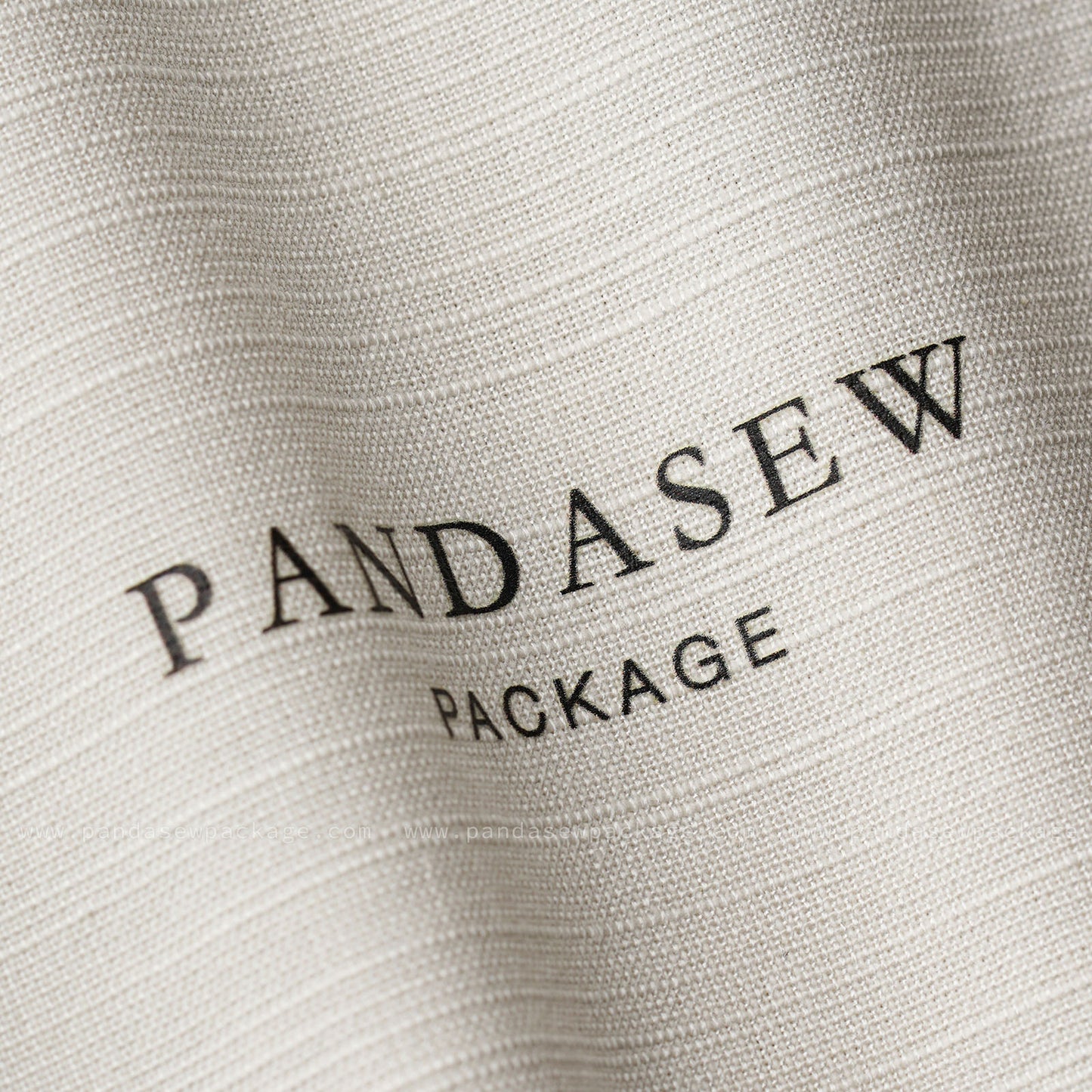 Close-up of custom logo printing on fabric. Crisp black ink branding on textured off-white cotton linen background