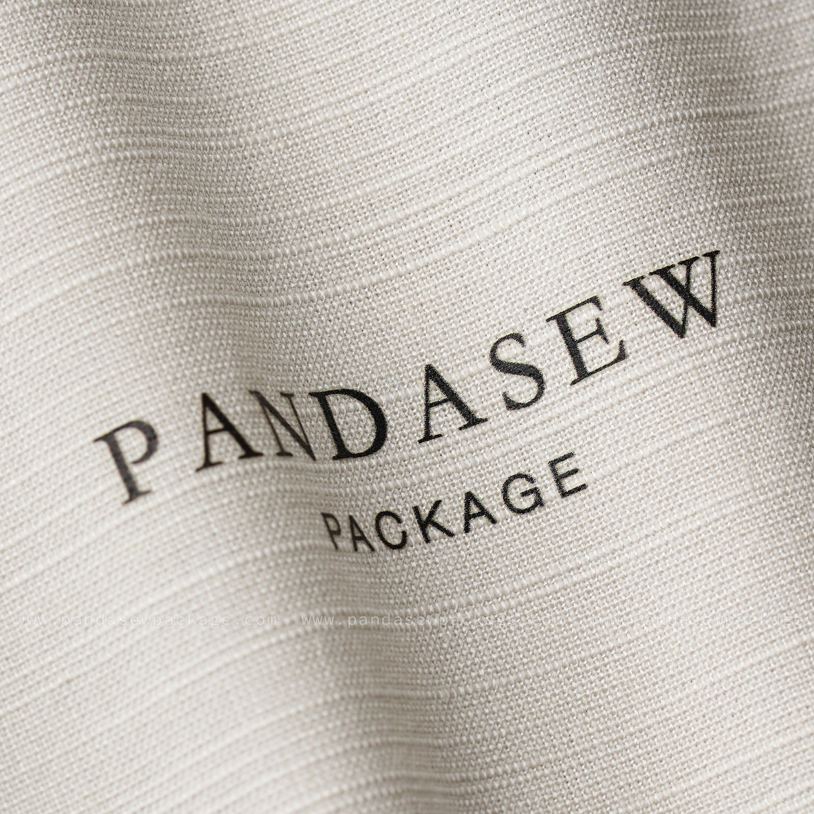 Close-up of custom logo printing on fabric. Crisp black ink branding on textured off-white cotton linen background