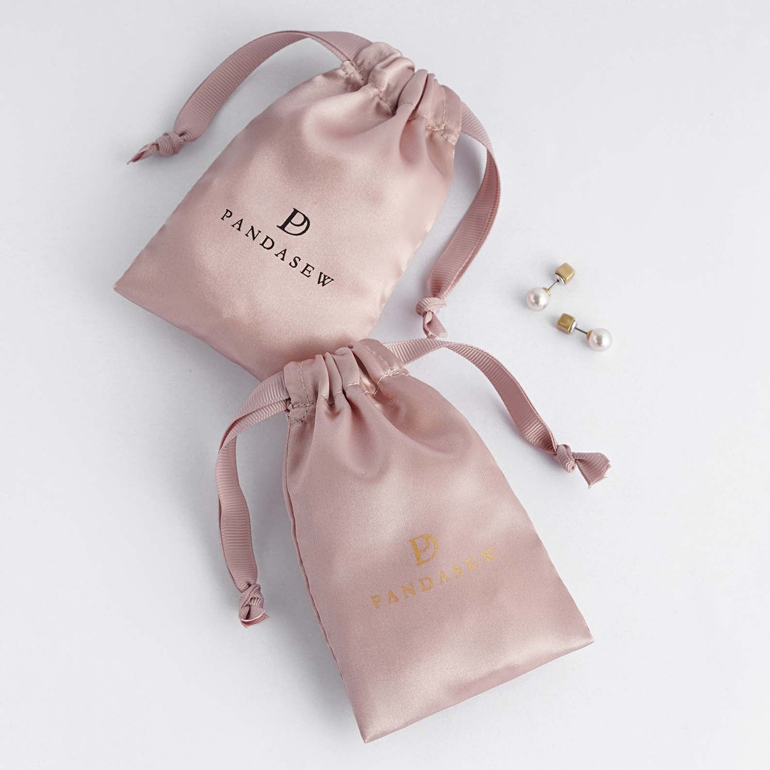pink color satin bag with black smooth satin string, black logo on pink satin